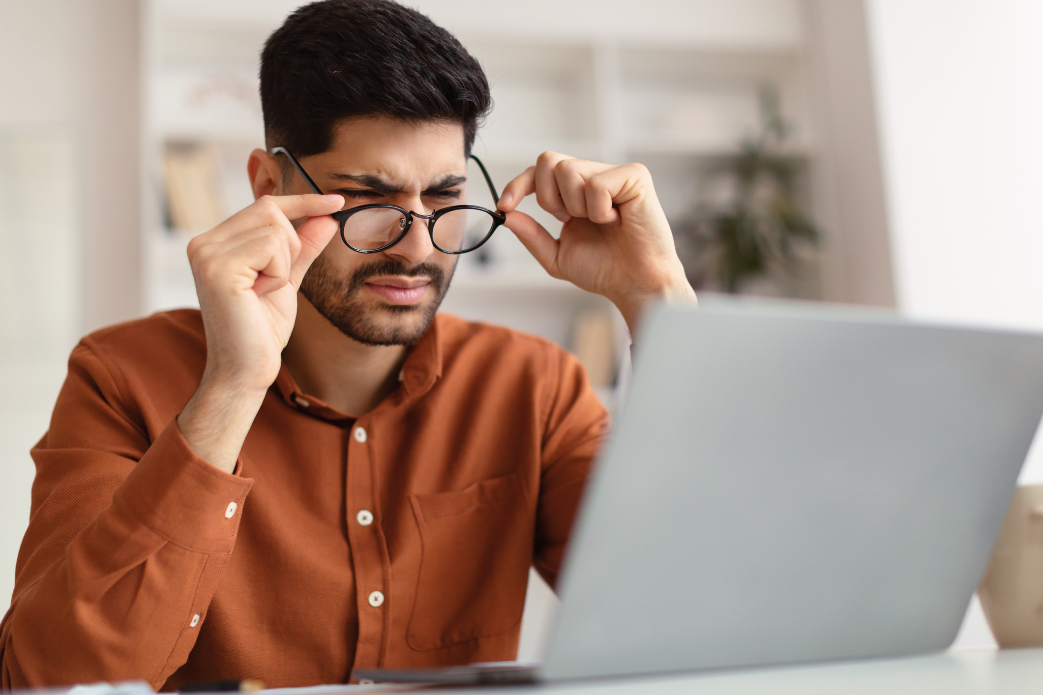 Confused Arab guy using laptop looking at screen